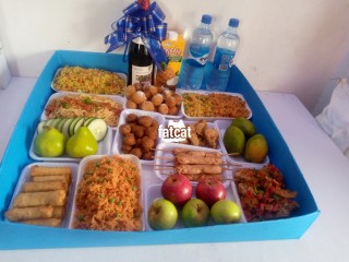 Foodtray emcomprises of jollof Rice, fried rice, sausage, protein, juice, wine, fruit